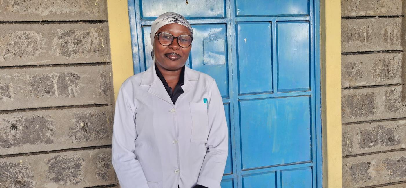 A clinic nurse in a white coat standing outside the clinic's blue door