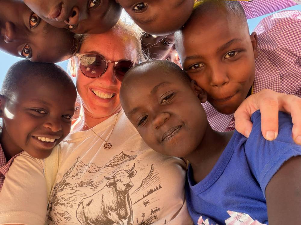 A team member surrounded by schoolchildren in Empukani, all of them leaning in close to the camera and smiling