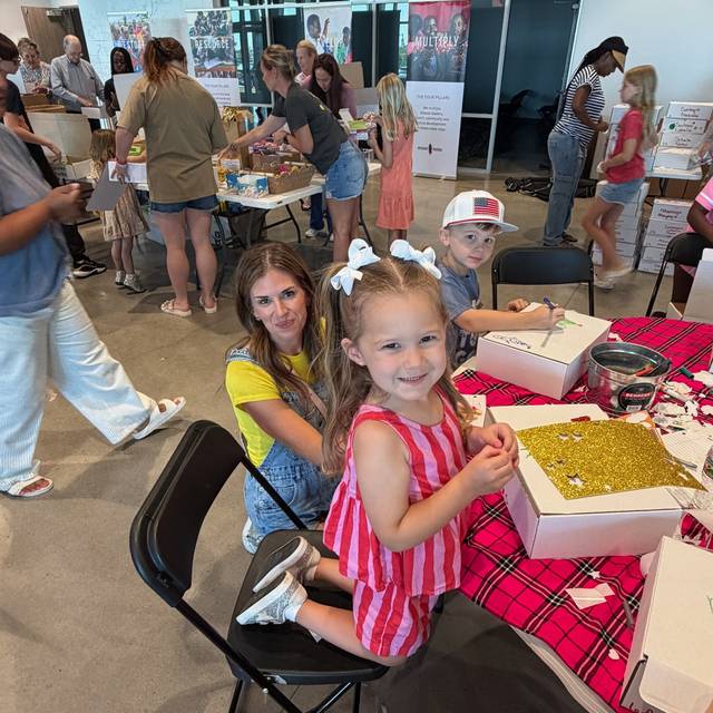 A young girl decorating a gift box with her mother at the Christmas in July tables