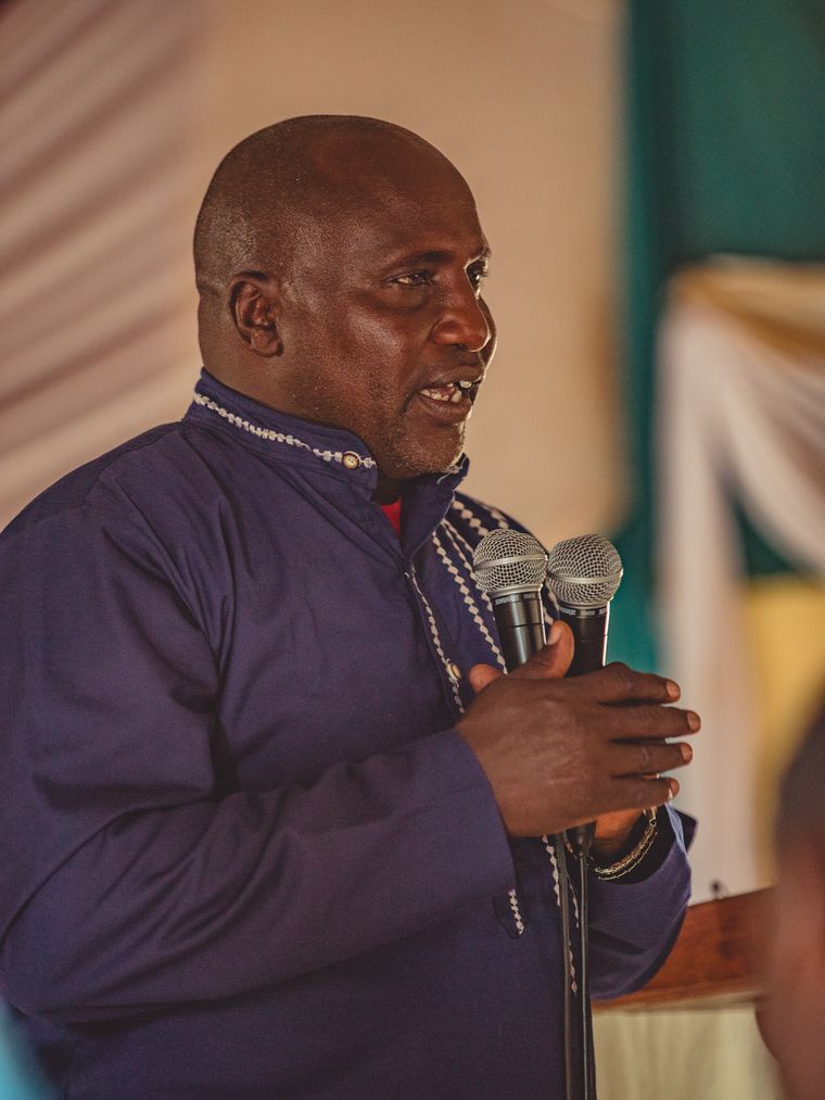 Pastor Timothy Moilo speaking, holding two microphones