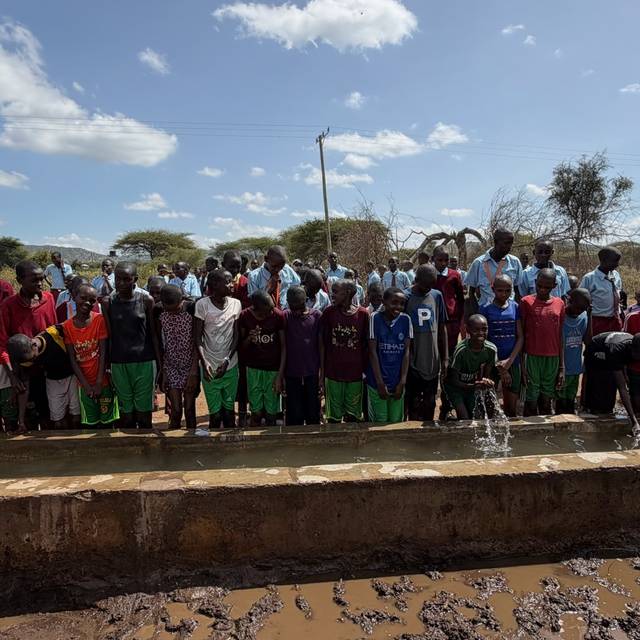 Students lined up along the concrete water trough at the school