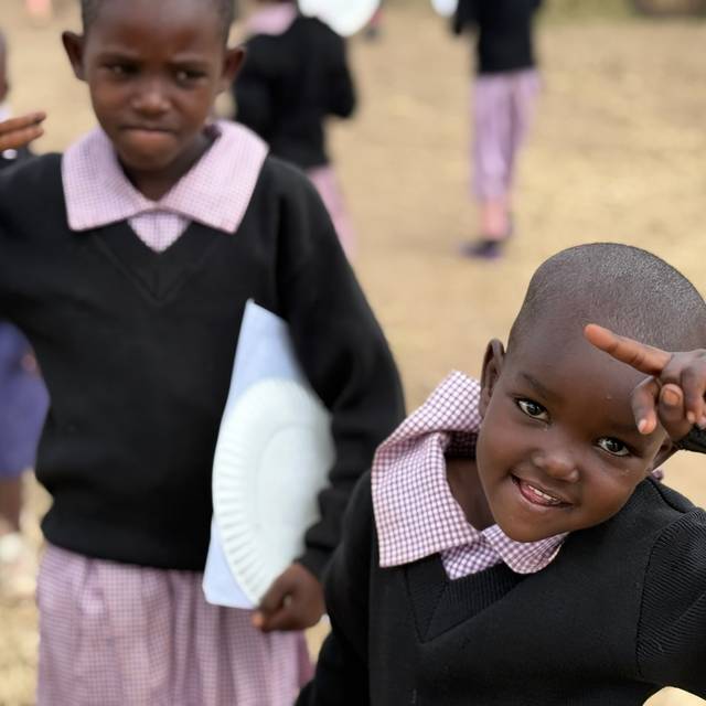 Two students at the school in Empukani, one grinning with a hand raised in a peace sign